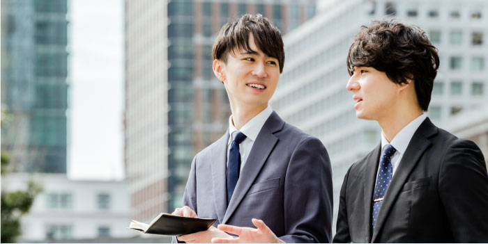 お仕事情報 - 会話する2人のビジネスパーソン